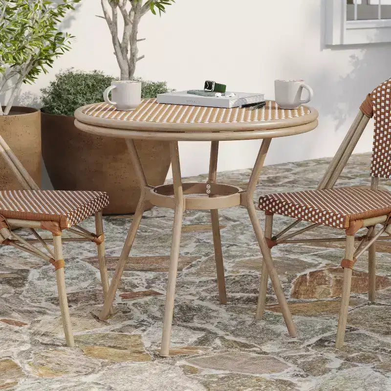 Table de style bistrot Celia de Merrick Lane avec plateau en verre trempé, rotin PE et cadre en métal finition bambou pour usage intérieur/extérieur.