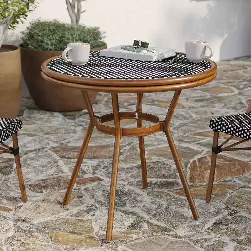 Table de style bistrot Celia de Merrick Lane avec plateau en verre trempé, rotin PE et cadre en métal finition bambou pour usage intérieur/extérieur.