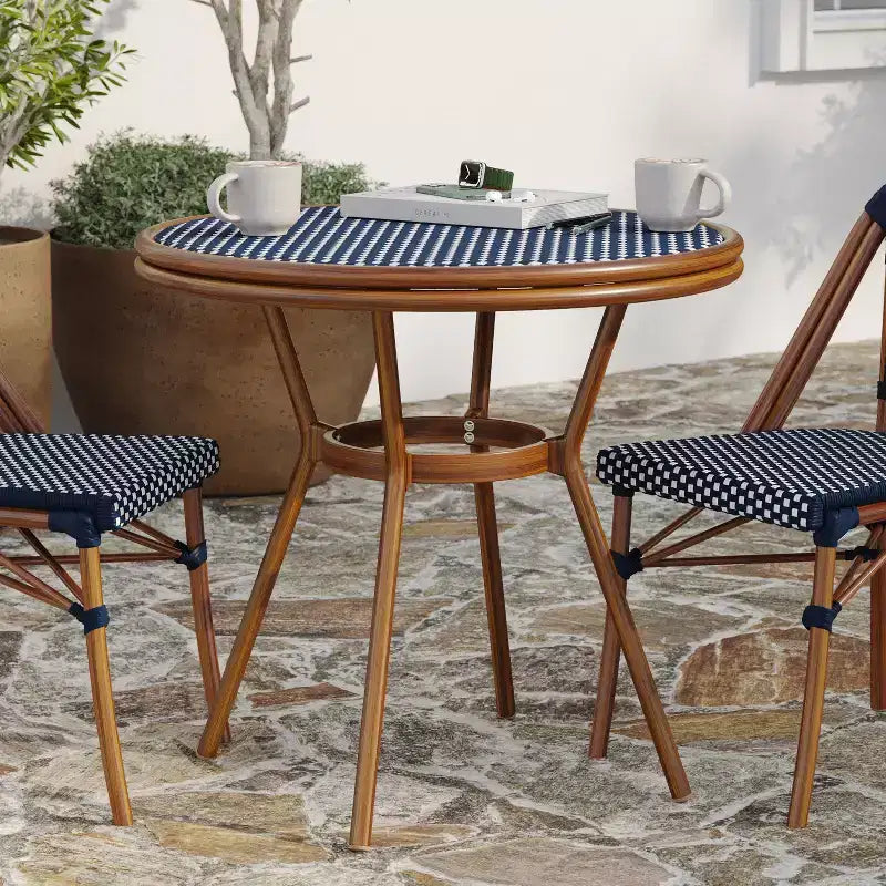 Table de style bistrot Celia de Merrick Lane avec plateau en verre trempé, rotin PE et cadre en métal finition bambou pour usage intérieur/extérieur.