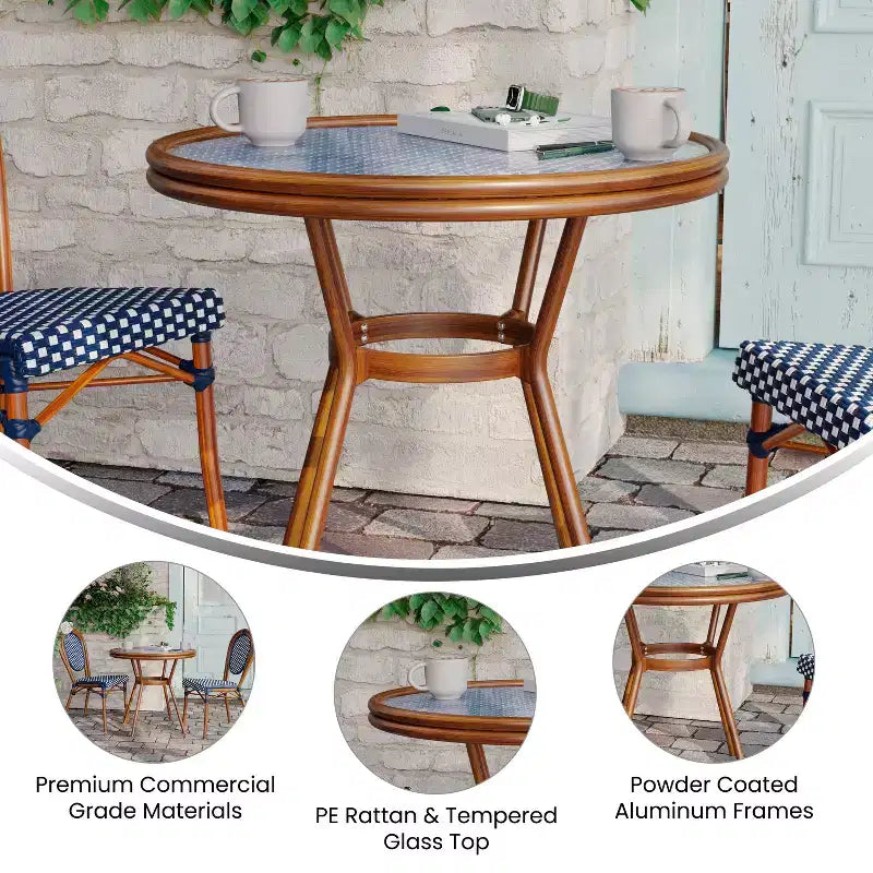 Table de style bistrot Celia de Merrick Lane avec plateau en verre trempé, rotin PE et cadre en métal finition bambou pour usage intérieur/extérieur.