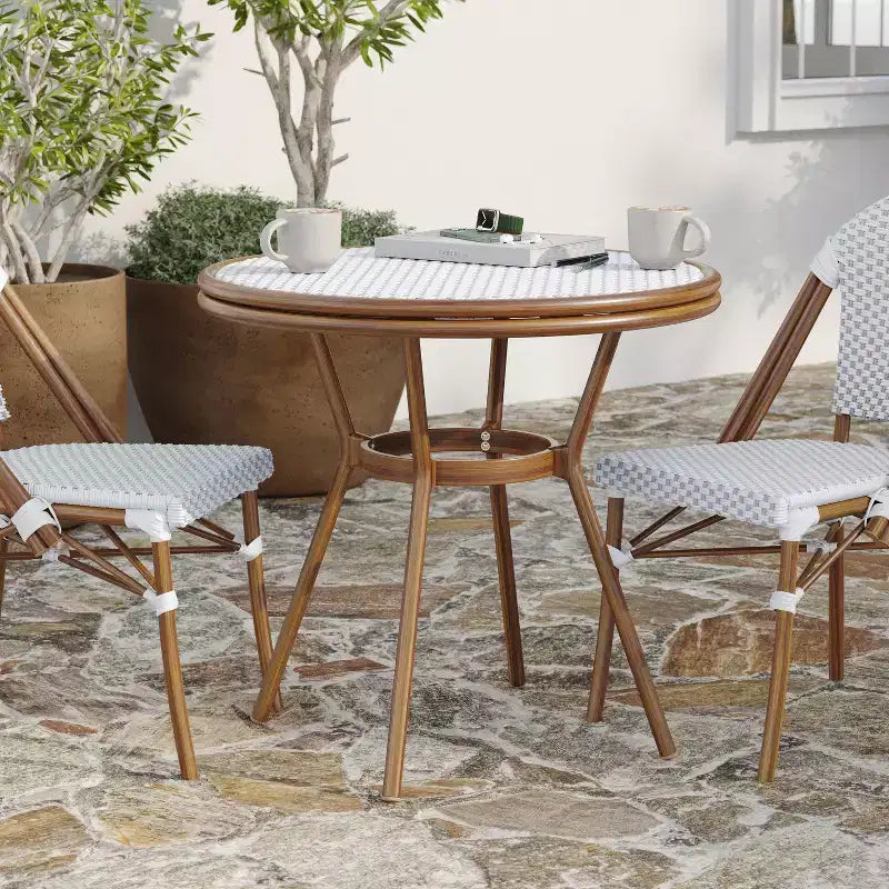 Table de style bistrot Celia de Merrick Lane avec plateau en verre trempé, rotin PE et cadre en métal finition bambou pour usage intérieur/extérieur.